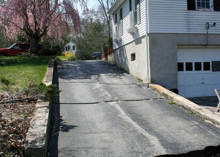 Residential driveway showing cracking and surface separation due to ground movement.
