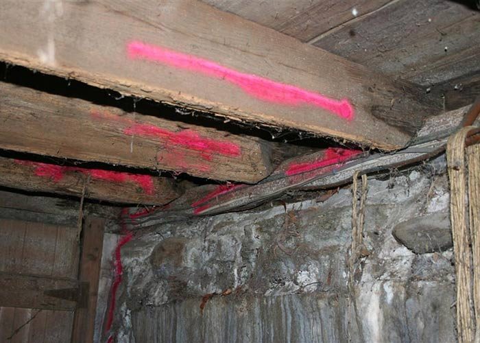 Basement framing with visible structural cracking and spray paint markings indicating areas of concern.